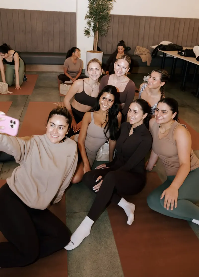 Guests smiling for a group selfie on their mats after a Pilates class